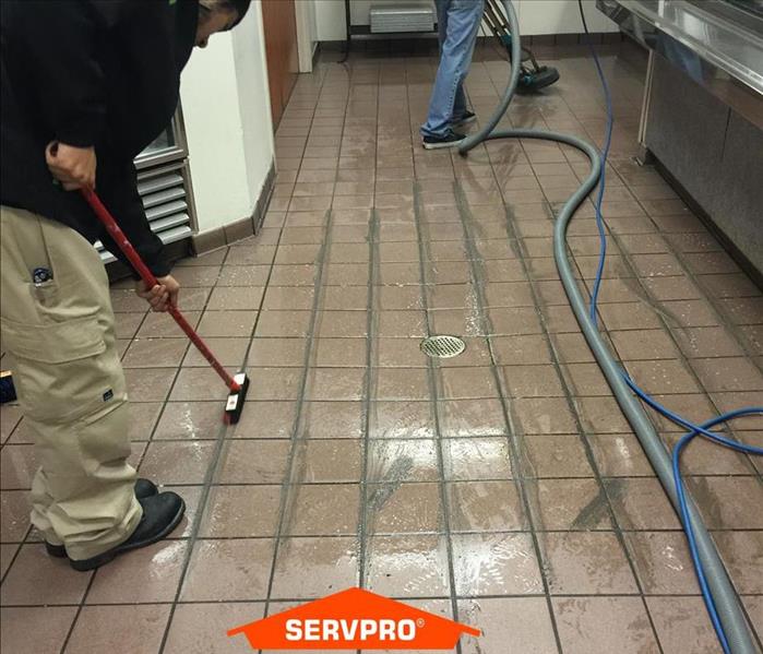 technicians cleaning dirt and grime from a commercial kitchen floor. 