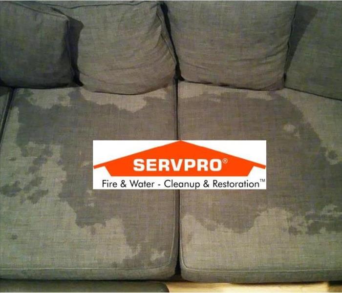 A dark colored ouch with a wet stain in the middle and the SERVPRO logo 