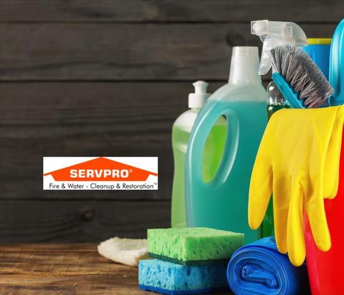 On the right side of the photo there is a red bucket with yellow gloves and other cleaning supplies inside and SERVPRO logo
