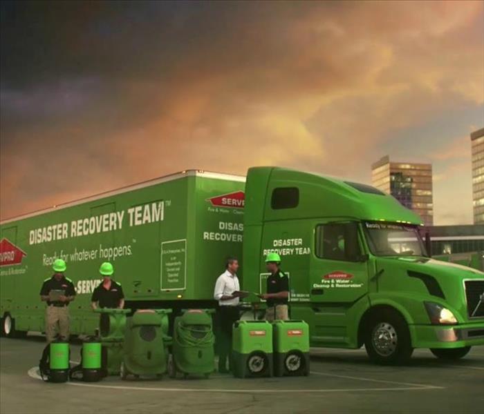 A SERVPRO photo of the big green SERVPRO 18 wheeler with SERVPRO employees standing next to it 